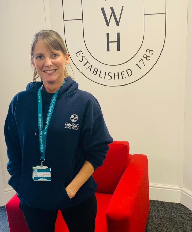 An Unmasked staff member smiling on-site in branded clothing, ready for a wellbeing drop-in