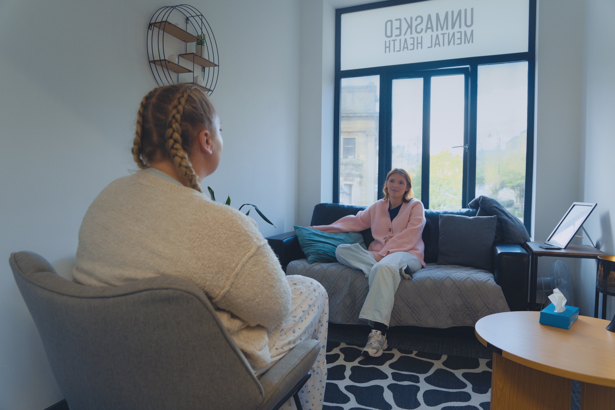 Young woman receiving counselling, sat comfortably in a calm setting