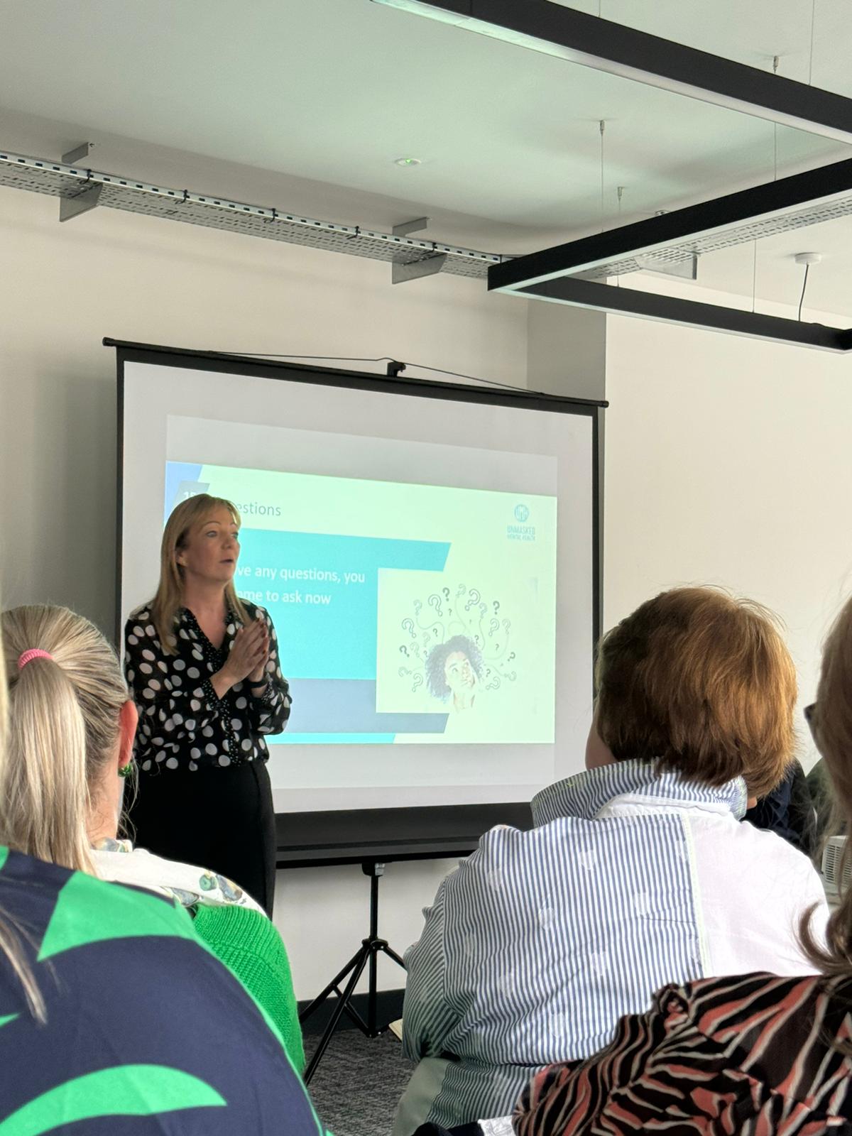 A trainer presenting to participants during a mental health awareness session