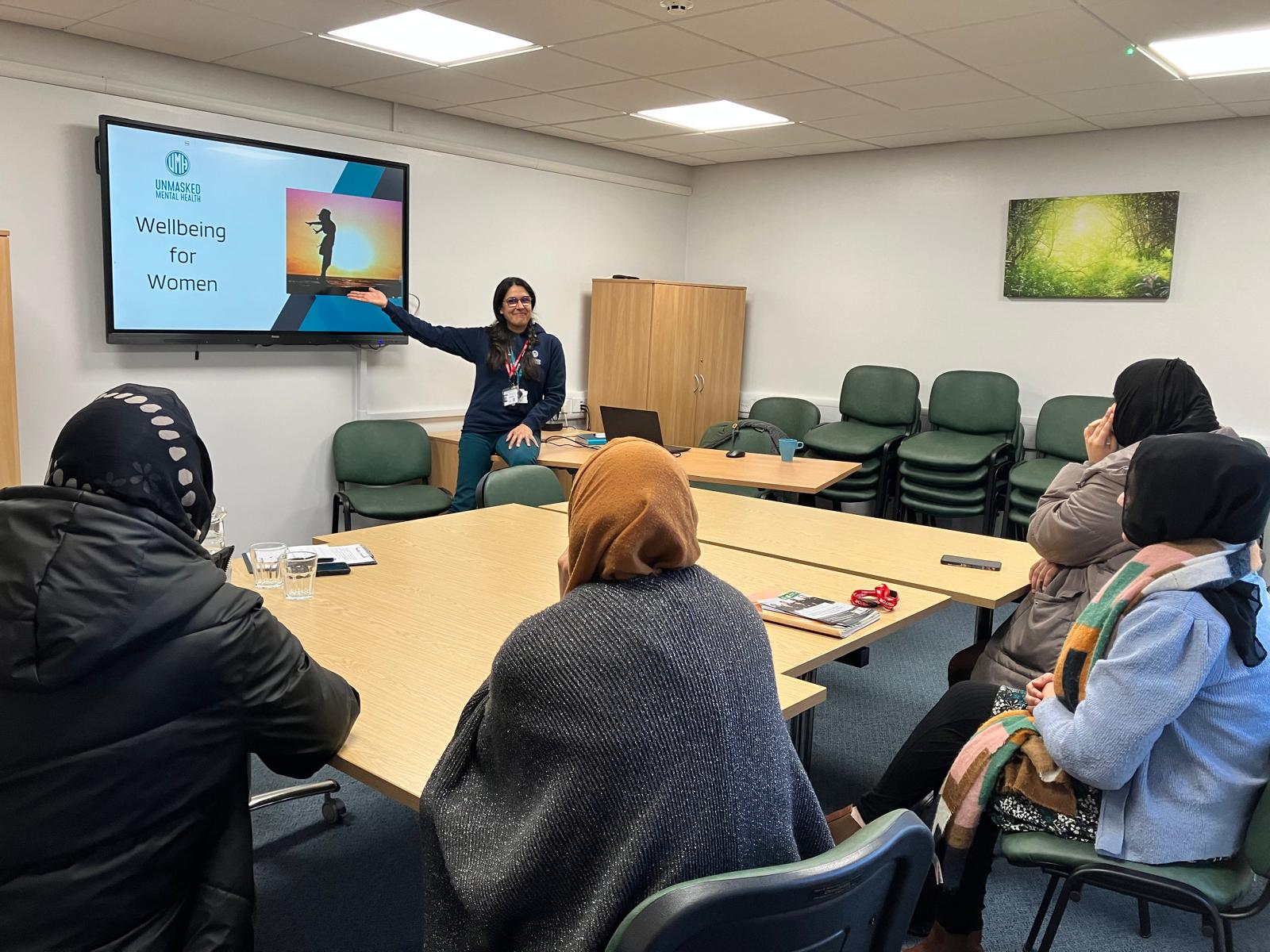 An Unmasked trainer delivering a wellbeing session to a small group around a table
