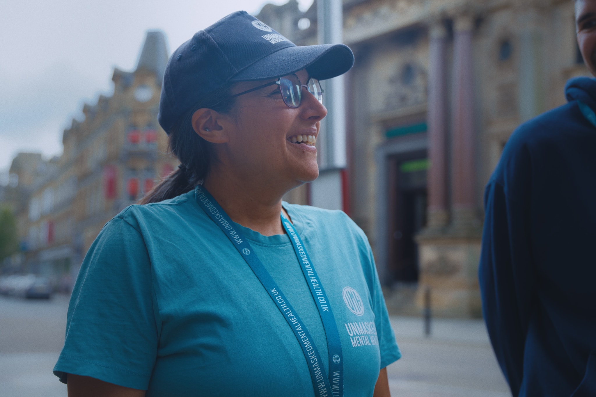 An Unmasked staff member smiling outdoors in branded clothing in Halifax
